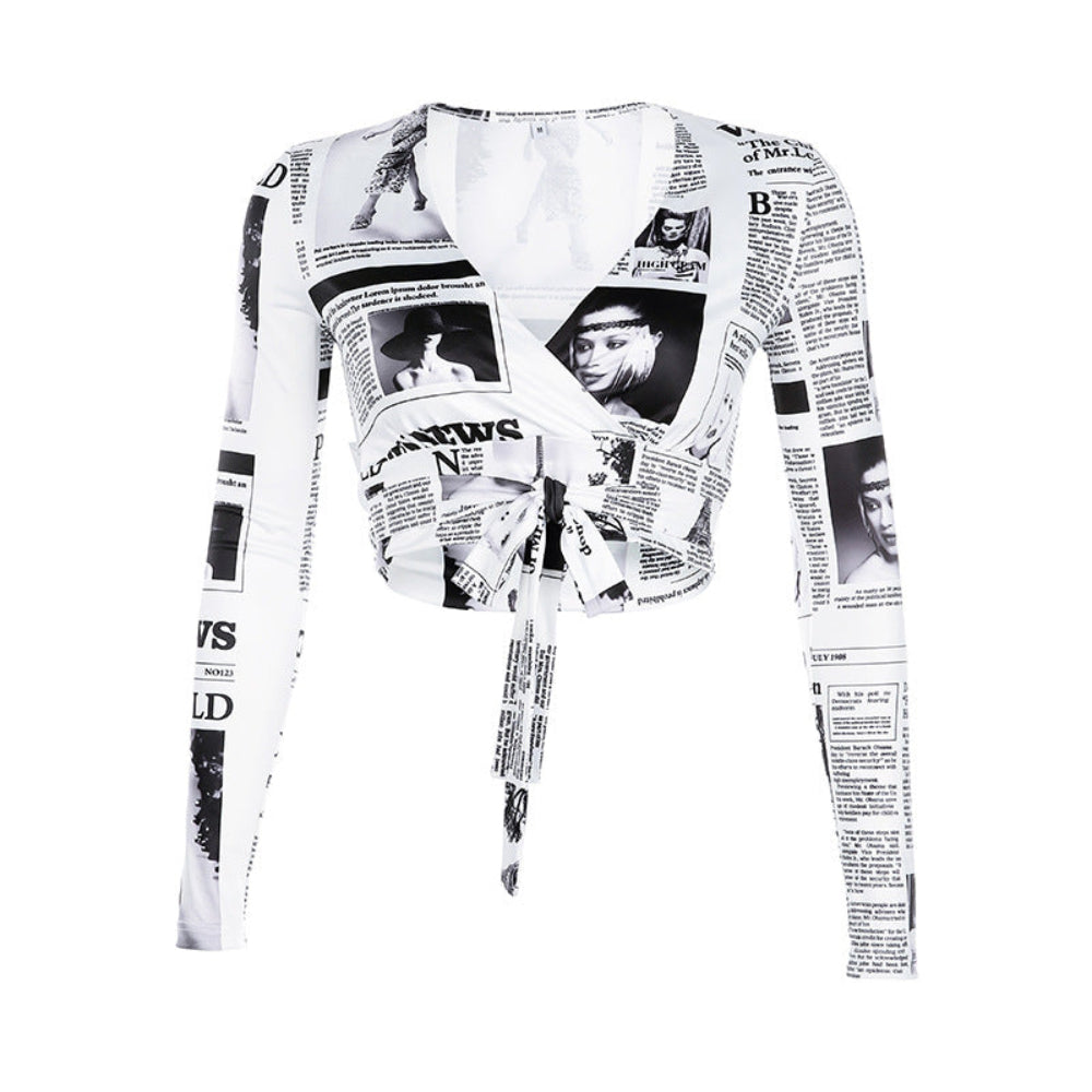 Black and white newspaper print long sleeve tie-front crop top with deep plunge V-neck, shown flat lay on white background.