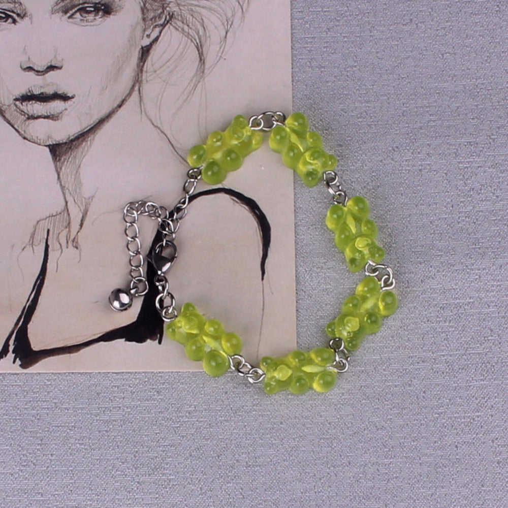 Lime green gummy bear charm bracelet with silver metal chain, lobster clasp, and black tassel, featuring multiple translucent bright lime green gummy bear charms, displayed on a textured background.
