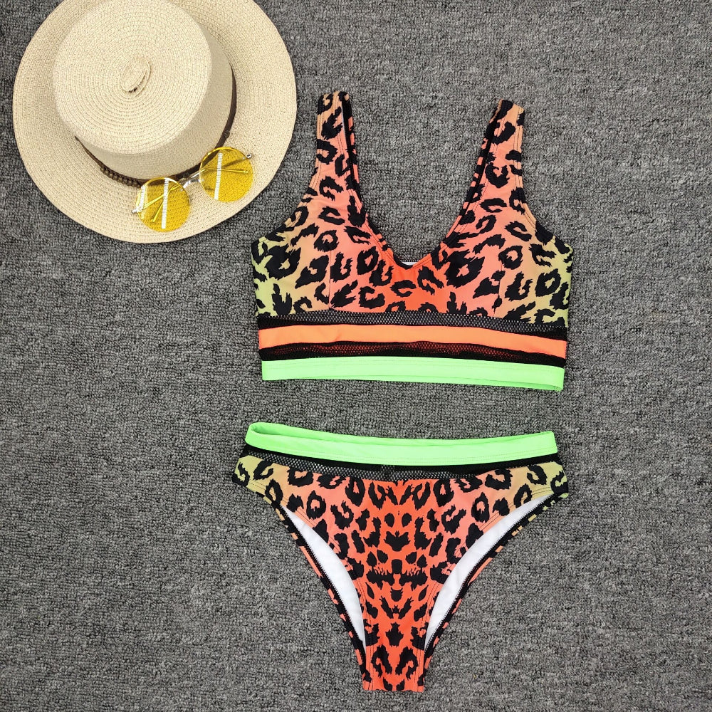 Leopard print bikini set with neon mesh colorblock detail flat lay with hat and sunglasses.