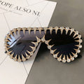 Gold spike crystal sunglasses with dark lenses – trendy designer statement sunnies with spikes and rhinestones, product flat lay on magazine.