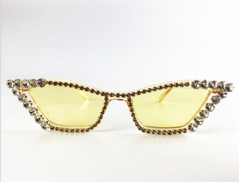 Gold cat-eye sunglasses with yellow lenses and crystal rhinestone trim, product photo on a white background.