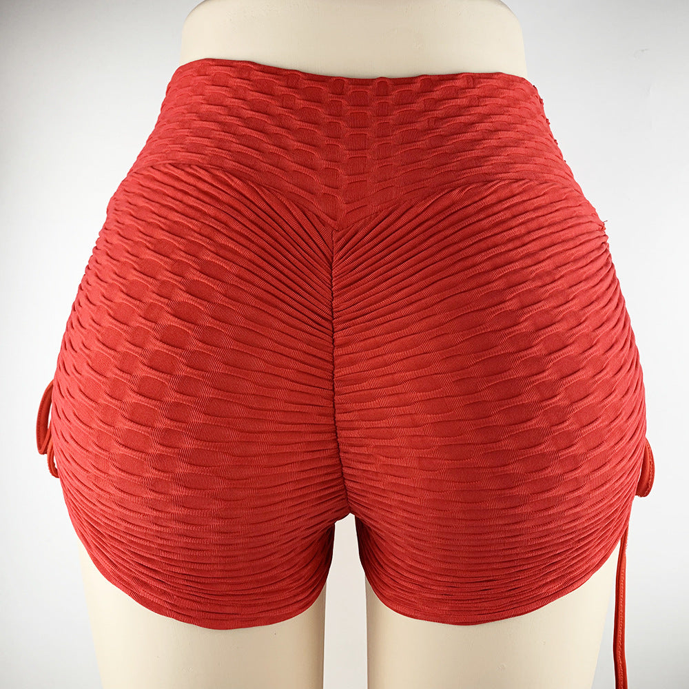 Red high-waisted ruched pleated shorts on a mannequin, shown from the back view with side tie details against a clean white studio background.