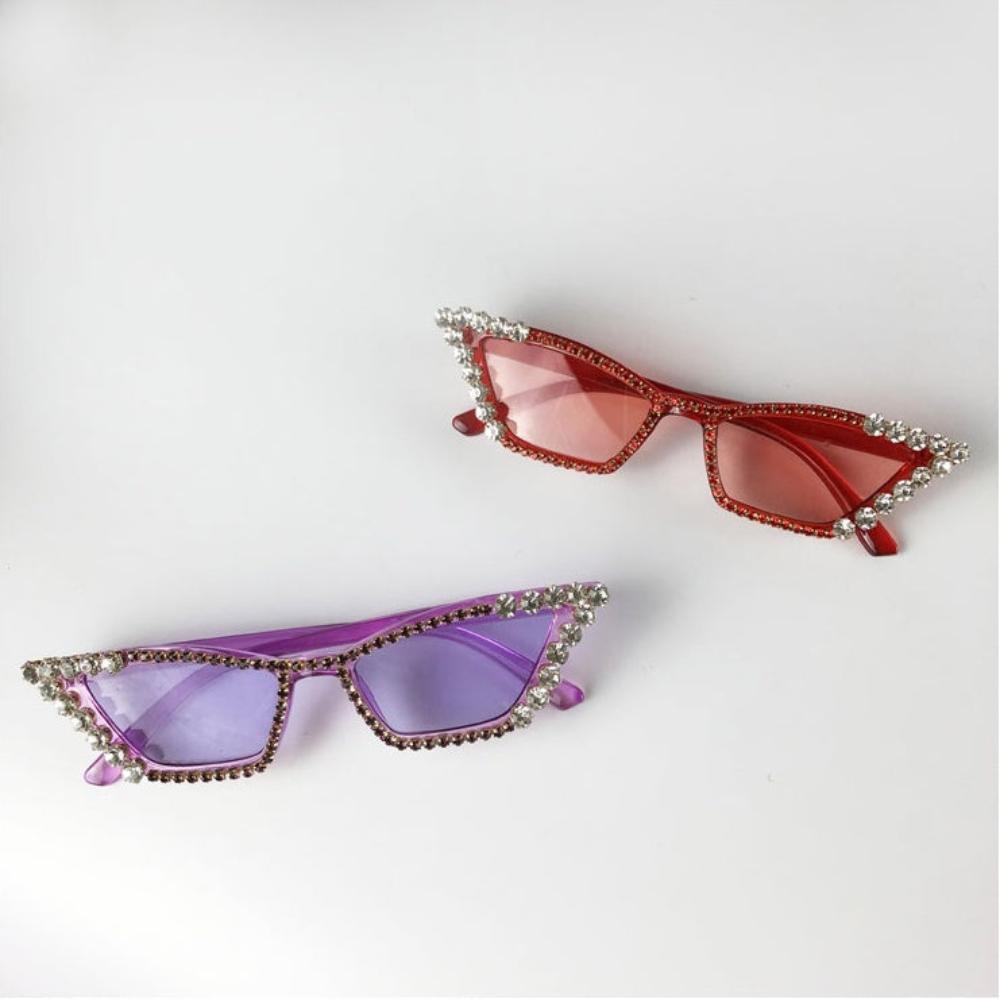 Red and purple rhinestone cat-eye sunglasses with tinted lenses, overhead product photo on a white background.