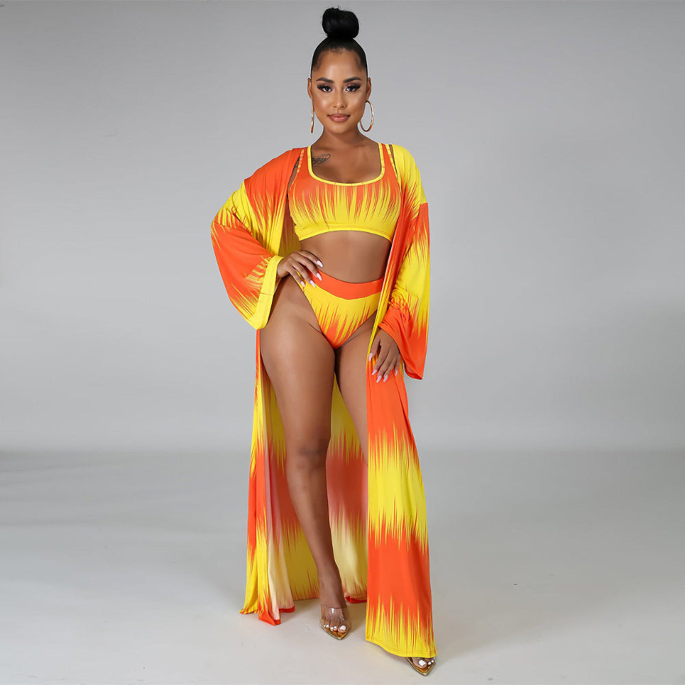 Woman wearing a vibrant orange and yellow bikini set with matching cover-up on a gray background