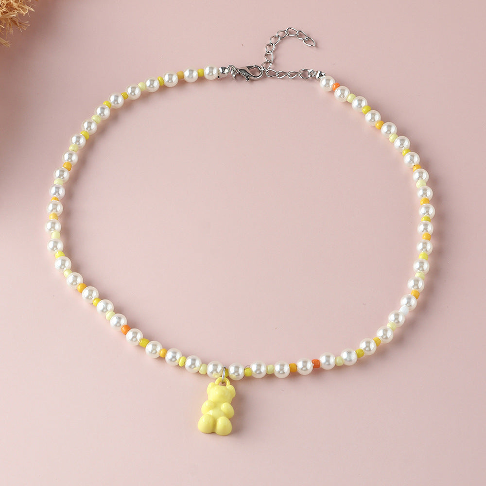 White pearl yellow gummy bear necklace – trendy colorful beaded choker with fun bear pendant, studio pink background.