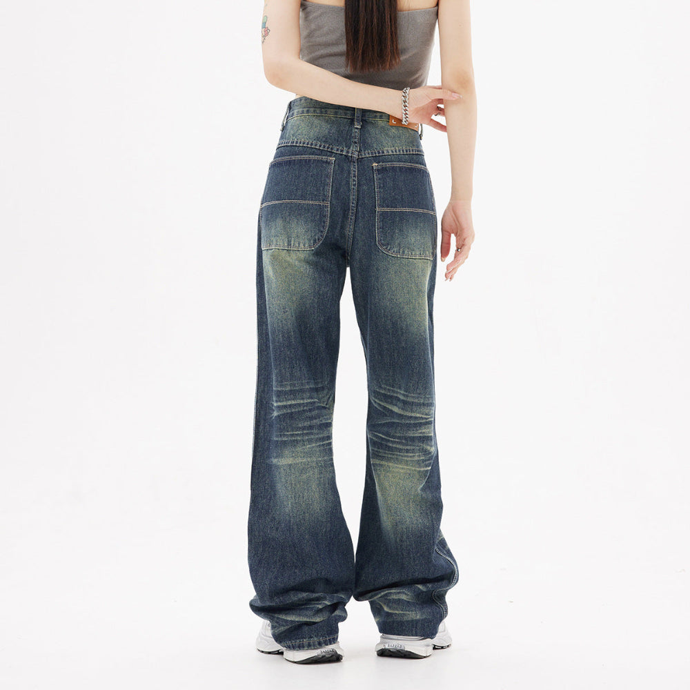 Woman modeling dark blue wide-leg baggy jeans with faded wash and back pockets, viewed from the back. Casual street-style fashion shot for Boutique Jolie.