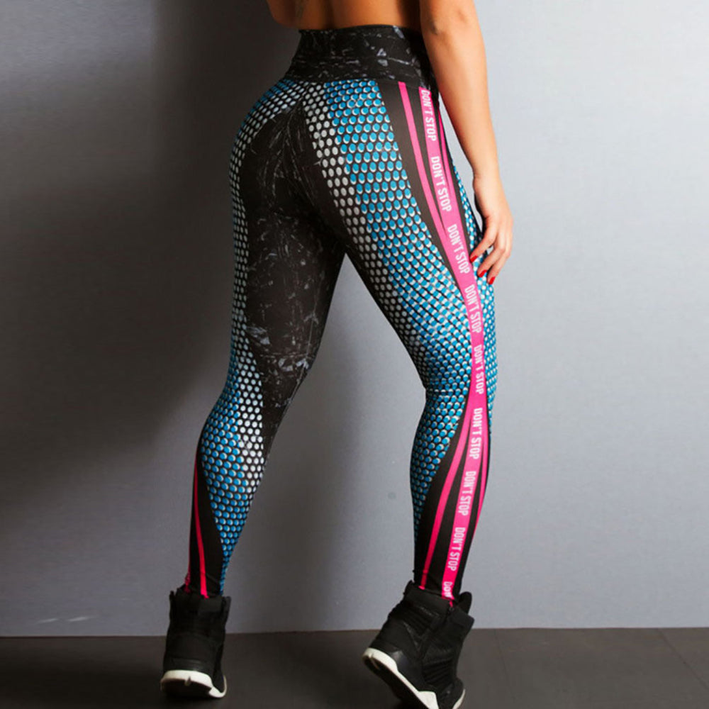 Woman modeling high-waisted athletic leggings with blue honeycomb pattern, black marble print, and bright pink side stripes featuring "DON'T STOP" text, shown from a rear three-quarter view with black sneakers against a plain gray studio background.