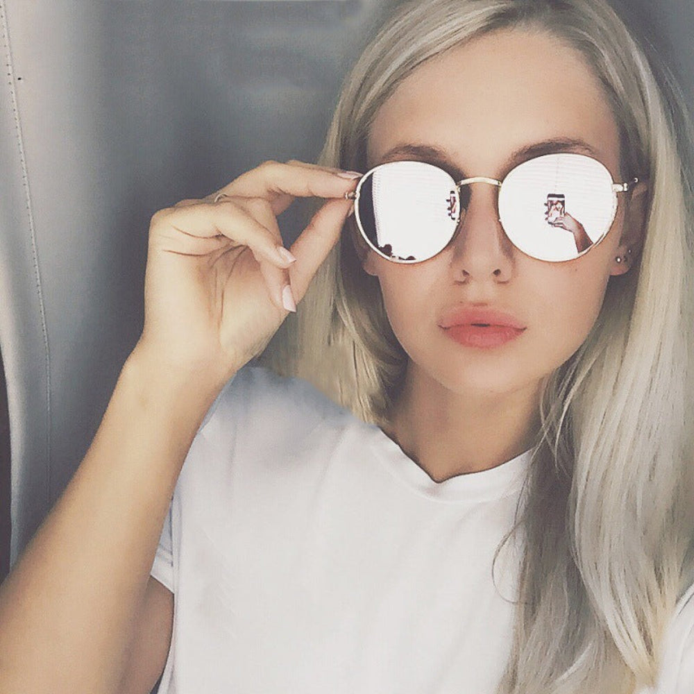 Stylish silver metal round sunglasses featuring bright white-silver mirrored reflective lenses, worn by model