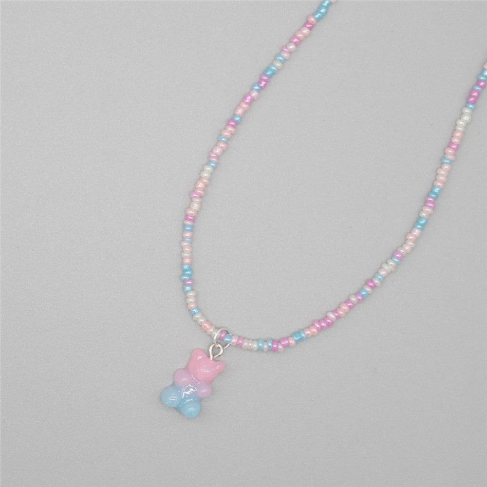 Pastel beaded necklace with a dreamy mix of soft pink, baby blue, and white seed beads paired with a translucent pink and blue gummy bear pendant. Delicate single-strand design laid flat on a light gray background, showcasing its sweet and whimsical style.