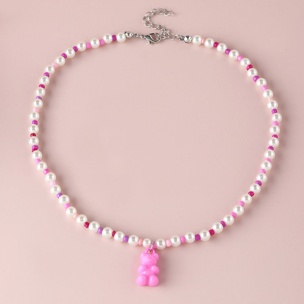 White pearl pink gummy bear necklace – trendy colorful beaded choker with fun bear pendant, studio pink background.