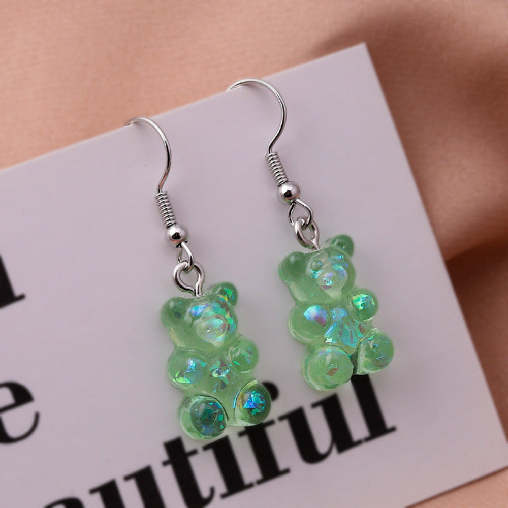 Translucent green holographic gummy bear earrings with shimmering iridescent finish and silver fishhook ear wires