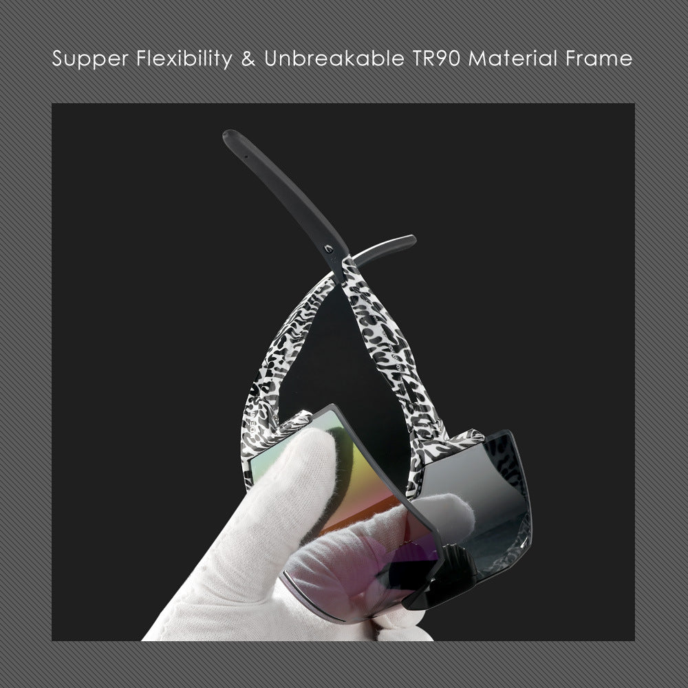 Sunglasses with a unique frame design held by a gloved hand against a dark background.
