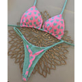 Pink and green bikini set on a decorative metal stand.