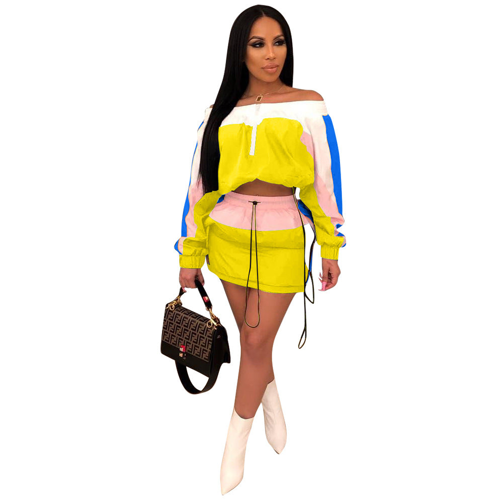 Woman in neon yellow, pink, and blue colorblock off-shoulder crop sweatshirt and matching mini skirt set with white boots, holding designer handbag against white background.