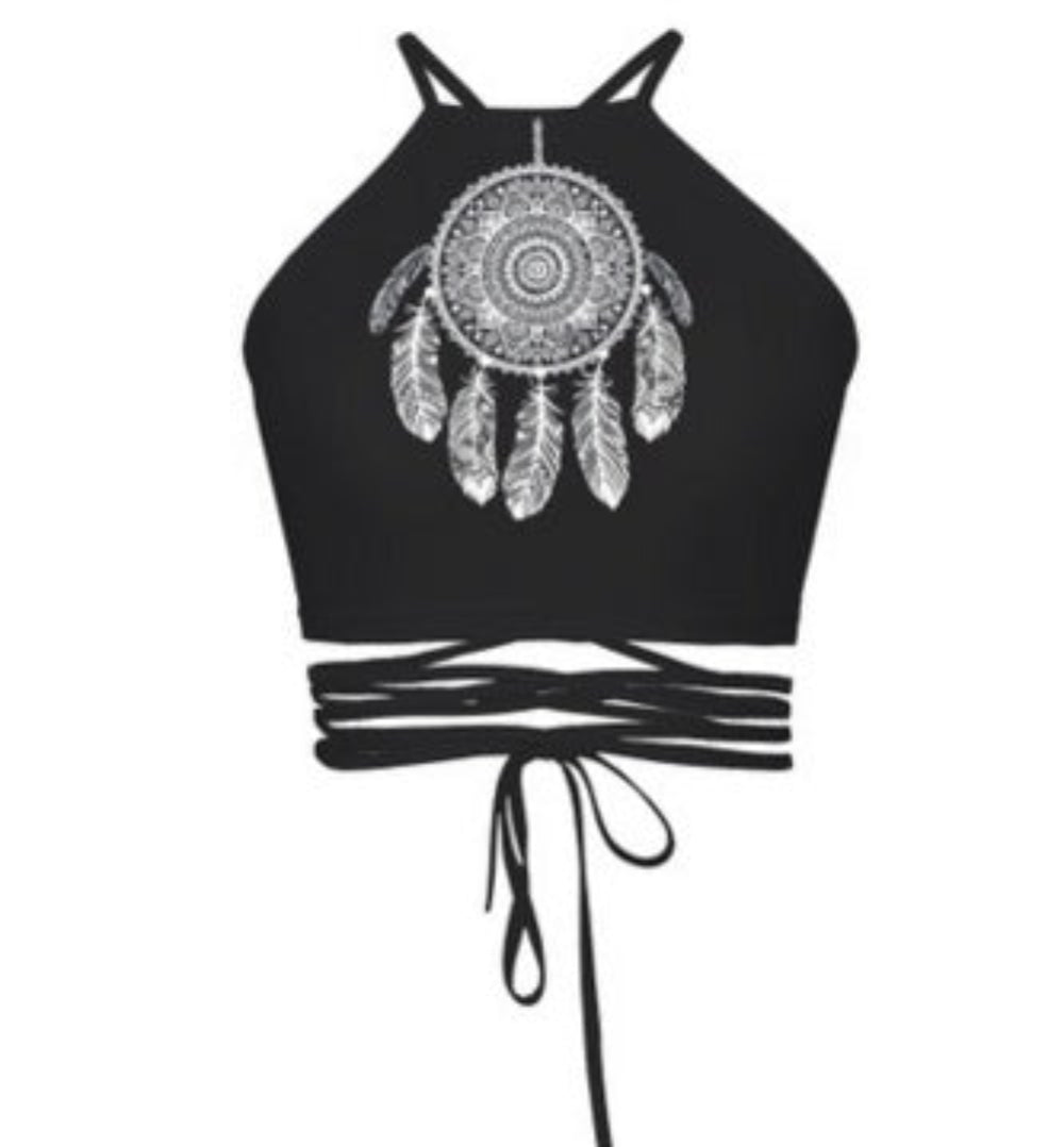 Black halter crop top with white dreamcatcher mandala graphic print and multi-strap tie-back detail, shown flat lay on white background.