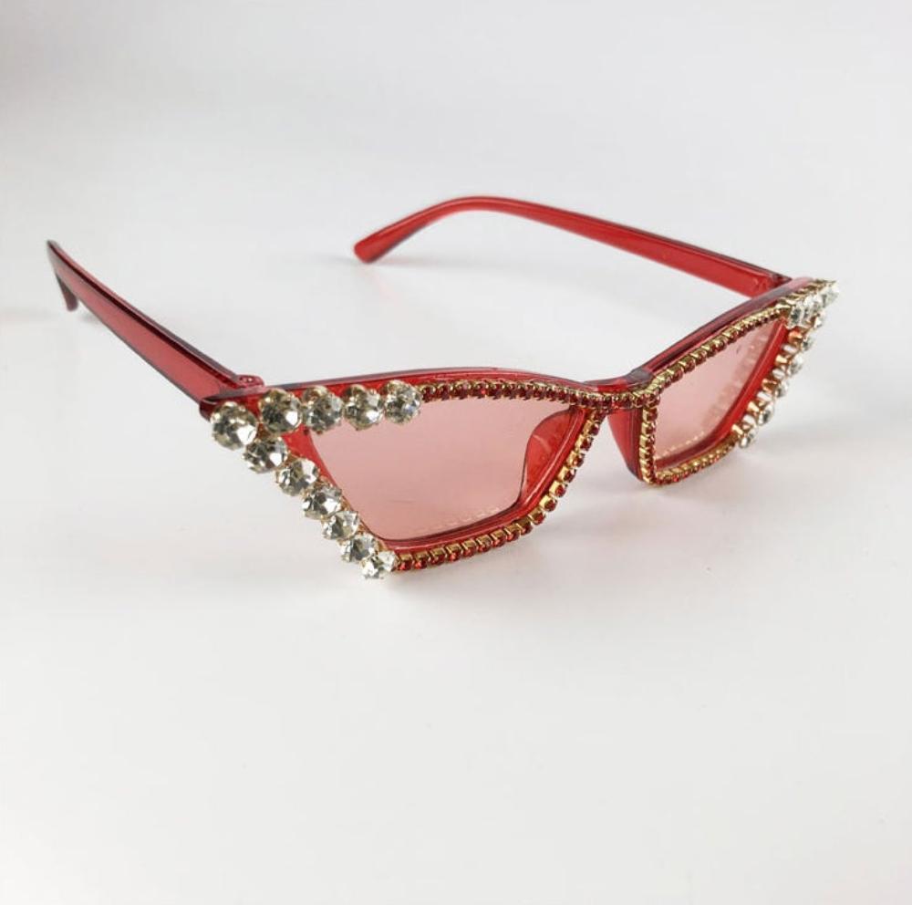 Red rhinestone cat-eye sunglasses with pink tinted lenses and gold crystal trim, product photo on a white background.