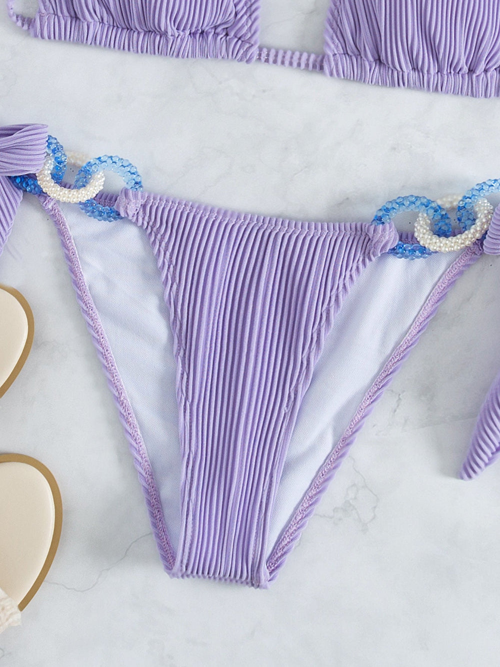 Lavender pleated bikini bottom with shell chain detail close-up.