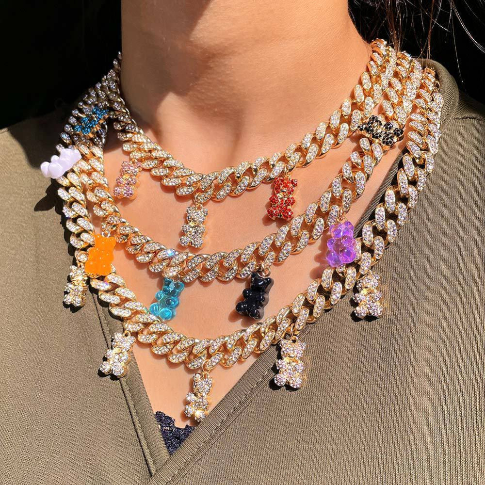 Model wearing a bold layered stack of multiple gold Cuban link choker necklaces fully iced with sparkling cubic zirconia stones, each adorned with colorful translucent teddy bear charms in white, pink, orange, blue, black, purple, and red. Glamorous, statement-making jewelry layered look.