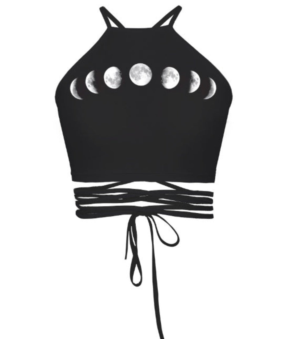Black halter crop top with moon phases print and multi-strap tie-back detail, shown flat lay on white background.