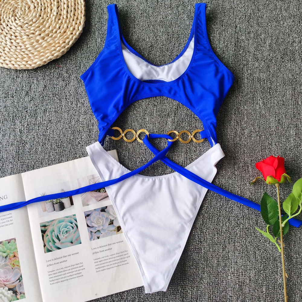 Royal blue cutout one-piece swimsuit with gold ring detail and tie waist flat lay.