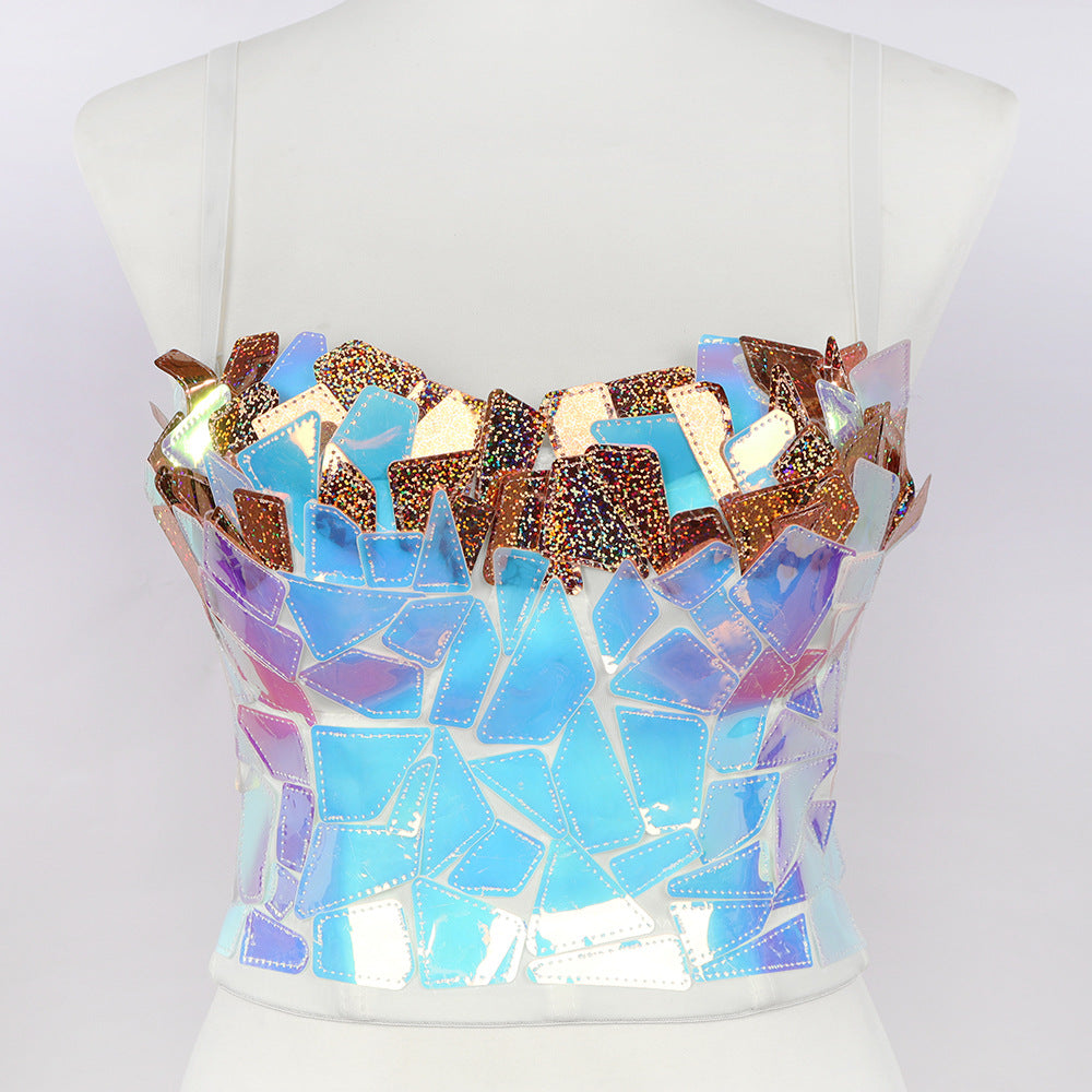 A white mannequin displaying a strapless mosaic crop top, featuring a dazzling design made of irregular, iridescent shards in vibrant shades of electric blue, turquoise, purple, and metallic gold. The fragmented, reflective pieces create a shimmering, broken-glass effect with holographic glitter details, giving the fitted bustier a bold, futuristic, and artistic look.