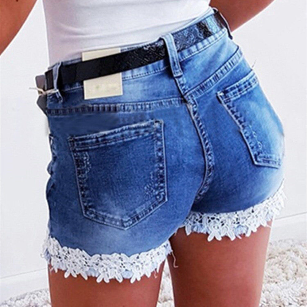Back view of woman modeling blue denim shorts with delicate white lace trim at the hem, back pockets, and a black belt. Close-up studio fashion shot highlighting the feminine fit and details for Boutique Jolie.