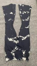 Black leggings with white abstract pattern laid flat on a gray textured surface, showing the full length and waistband details.