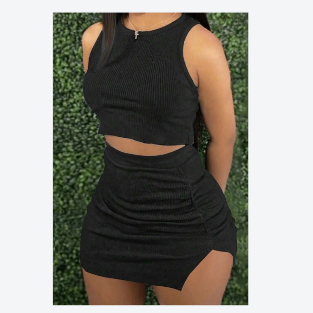 Black sleeveless top and skirt set worn by a person against a green hedge background