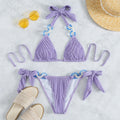 Lavender pleated bikini set with shell detail and bow ties flat lay with accessories.