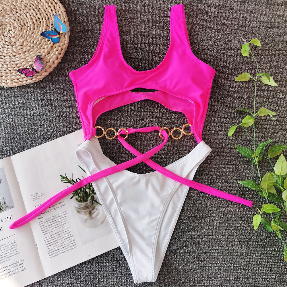 Hot pink cutout one-piece swimsuit with gold ring detail and tie waist flat lay.