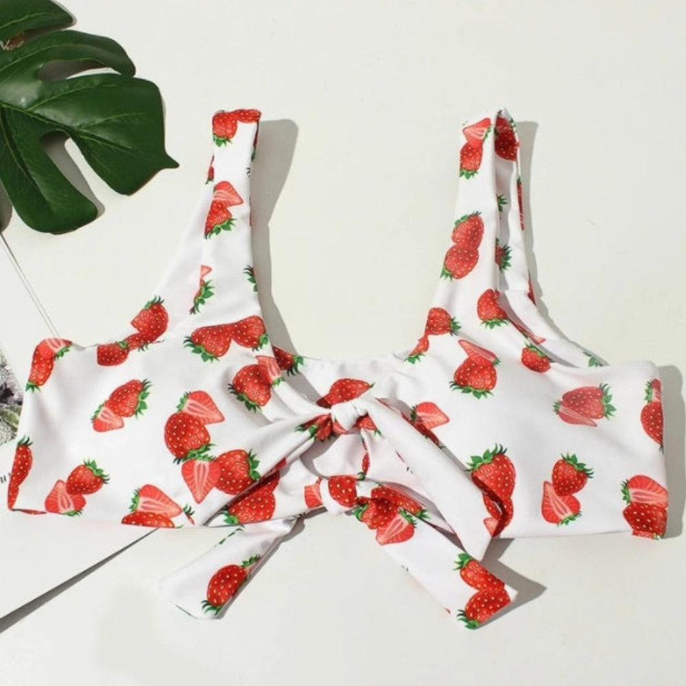White bikini set with red strawberry pattern on a light background