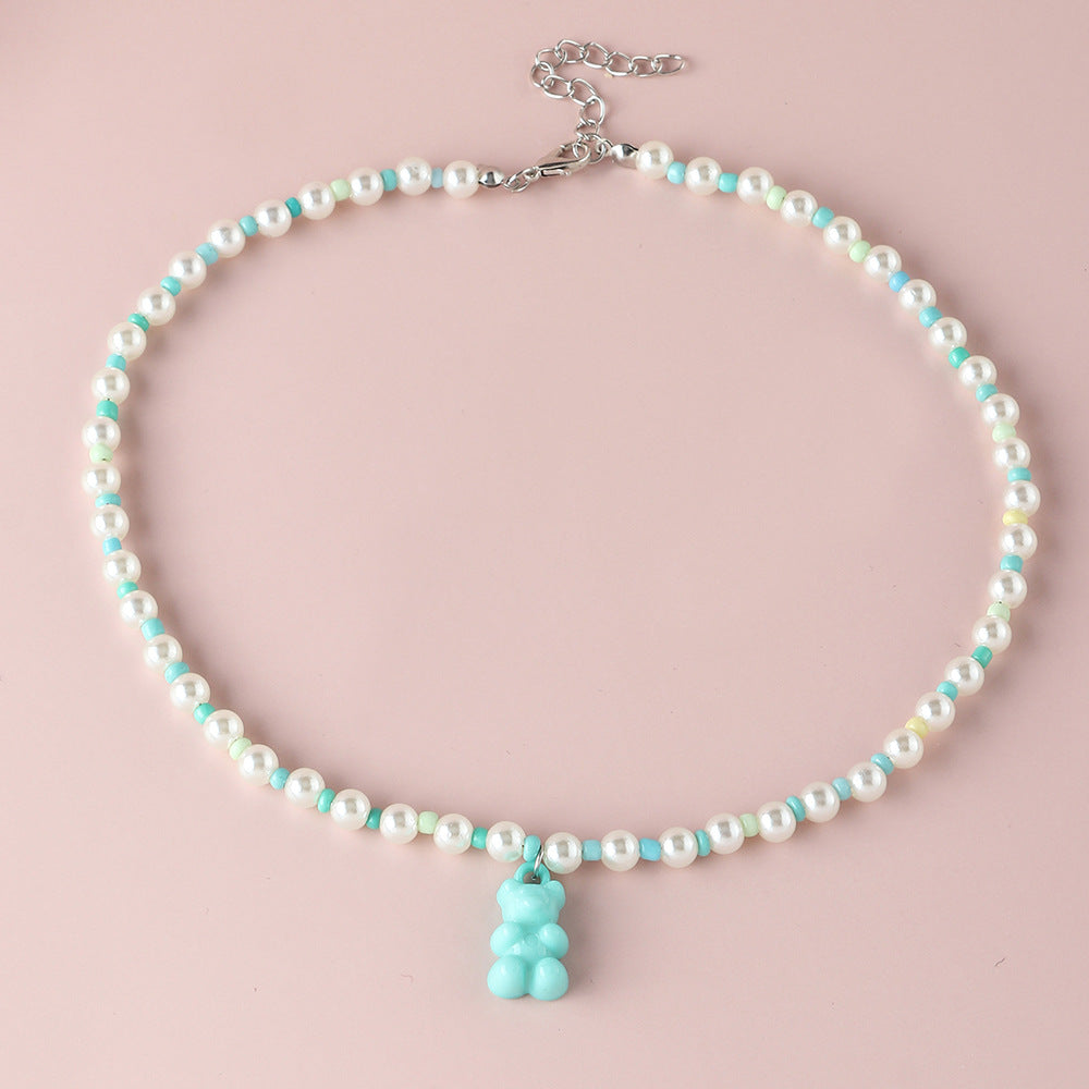 White pearl  blue gummy bear necklace – trendy colorful beaded choker with fun bear pendant, studio pink background.