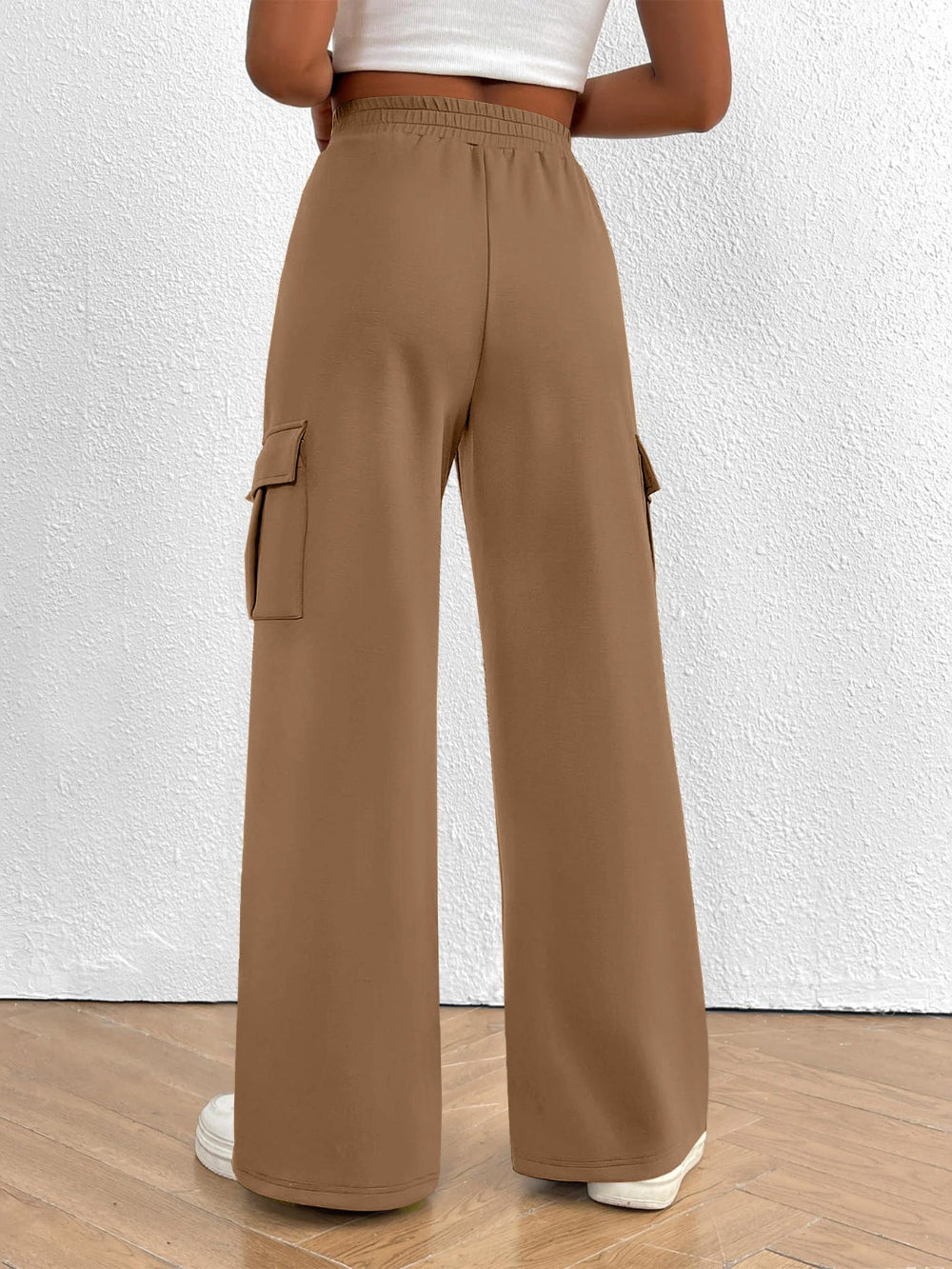 Person wearing tan cargo pants against a white wall.