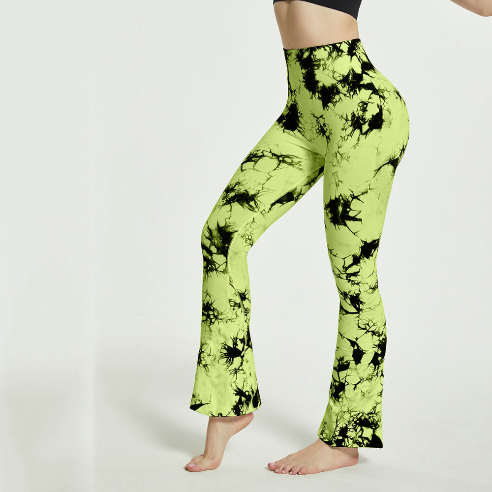 Woman modeling lime green and black tie-dye high-waisted flared pants, shown from a side view while standing barefoot against a clean white studio background.