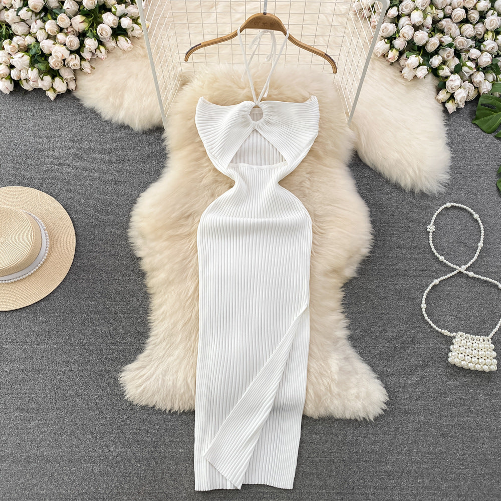 White ribbed knit halter maxi dress with front keyhole cutout laid flat on fur rug with straw hat and pearl bag.