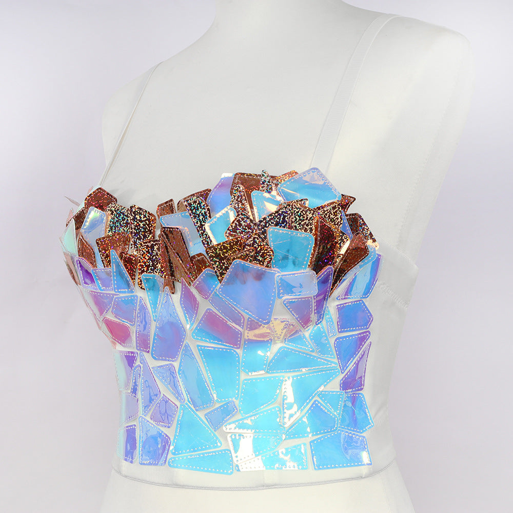 Mannequin wearing a bold iridescent mosaic crop top featuring shattered mirror fragments in holographic blue, purple, and copper tones. The statement piece has a structured bandeau style with shimmering, reflective shattered glass effect.