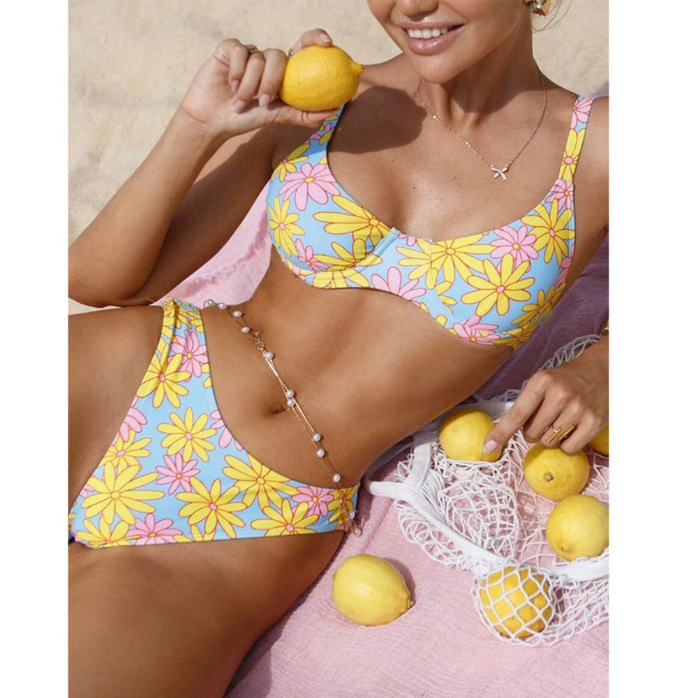 Woman in a colorful floral bikini holding lemons on a beach.