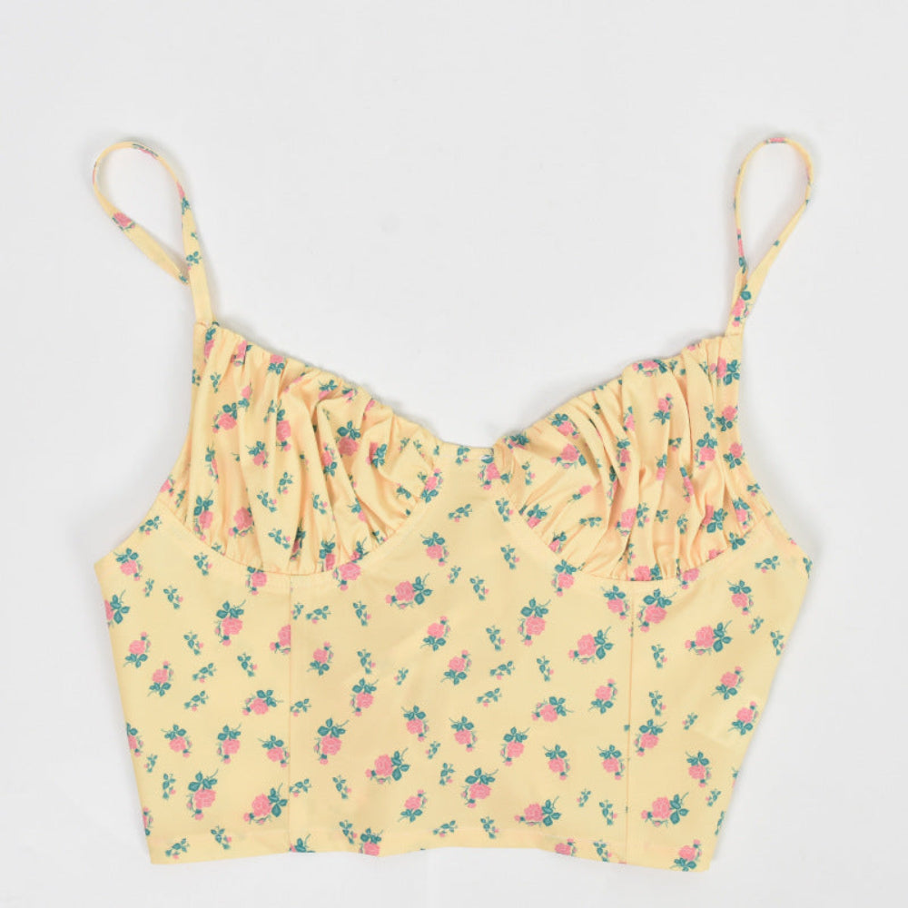 Yellow floral print ruched crop cami with thin spaghetti straps, shown flat lay on white background.