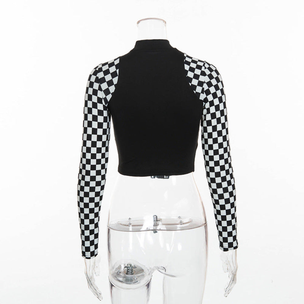 Back view of a black long-sleeve crop top on a transparent mannequin. The top features a solid black body with a high mock neck and bold black-and-white checkerboard pattern on the sleeves.