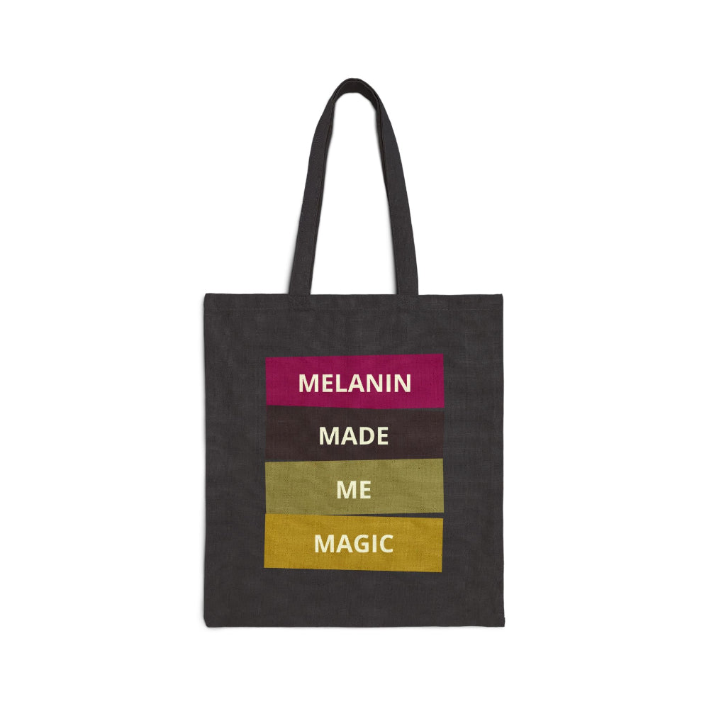 Black canvas tote bag with "MELANIN MADE ME MAGIC" graphic in stacked colored blocks.