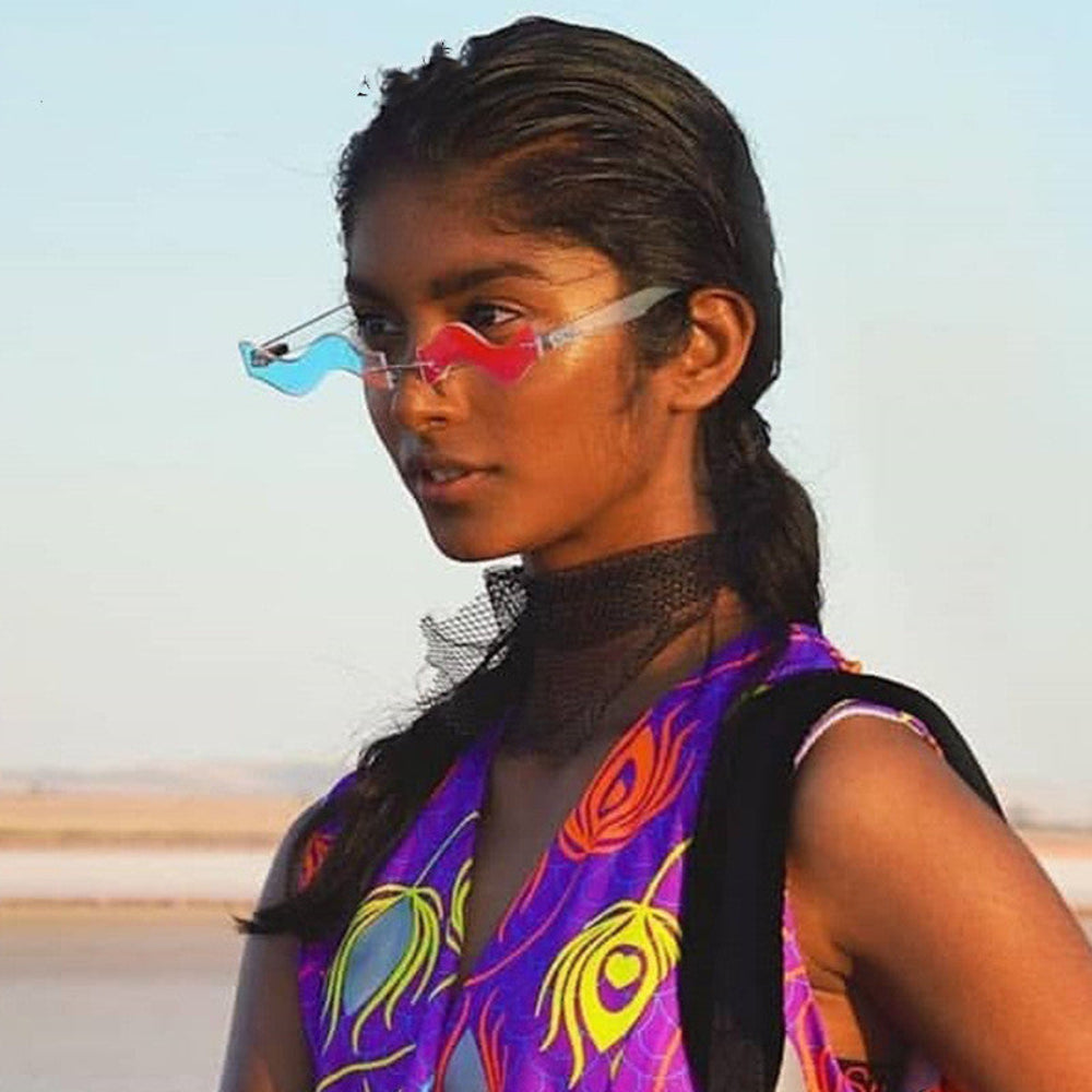 Model wearing rimless wavy sunglasses with one blue lens and one pink lens.