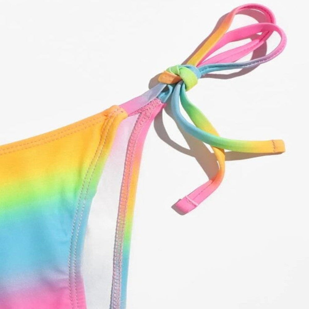 Rainbow tie-dye bikini bottom close-up with adjustable tie-side strings and knot detail.