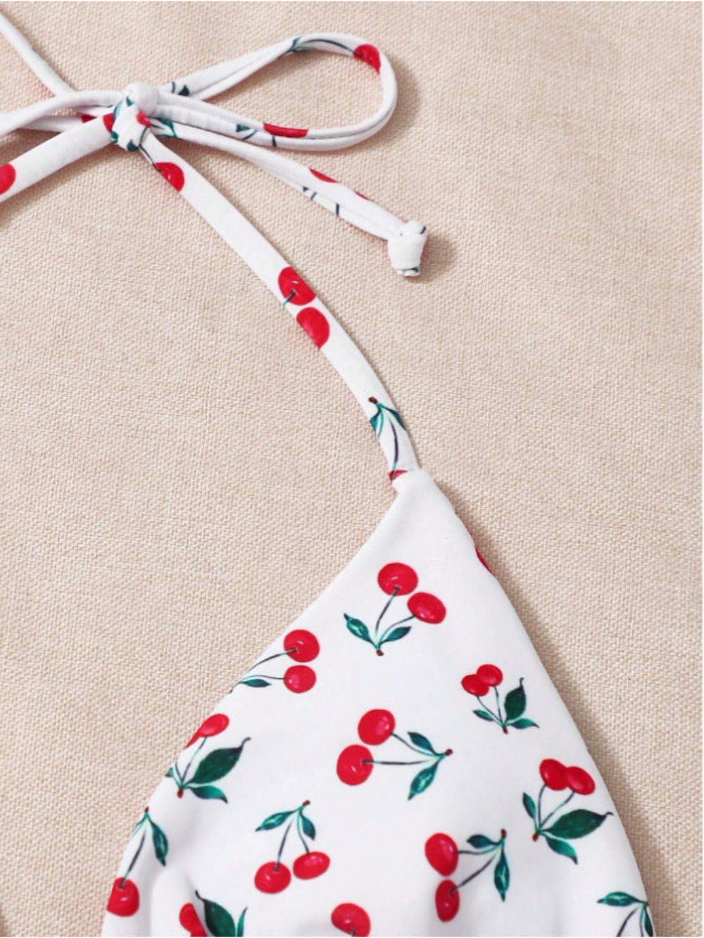 Cherry print halter bikini top close-up with tie straps and triangle cup detail.