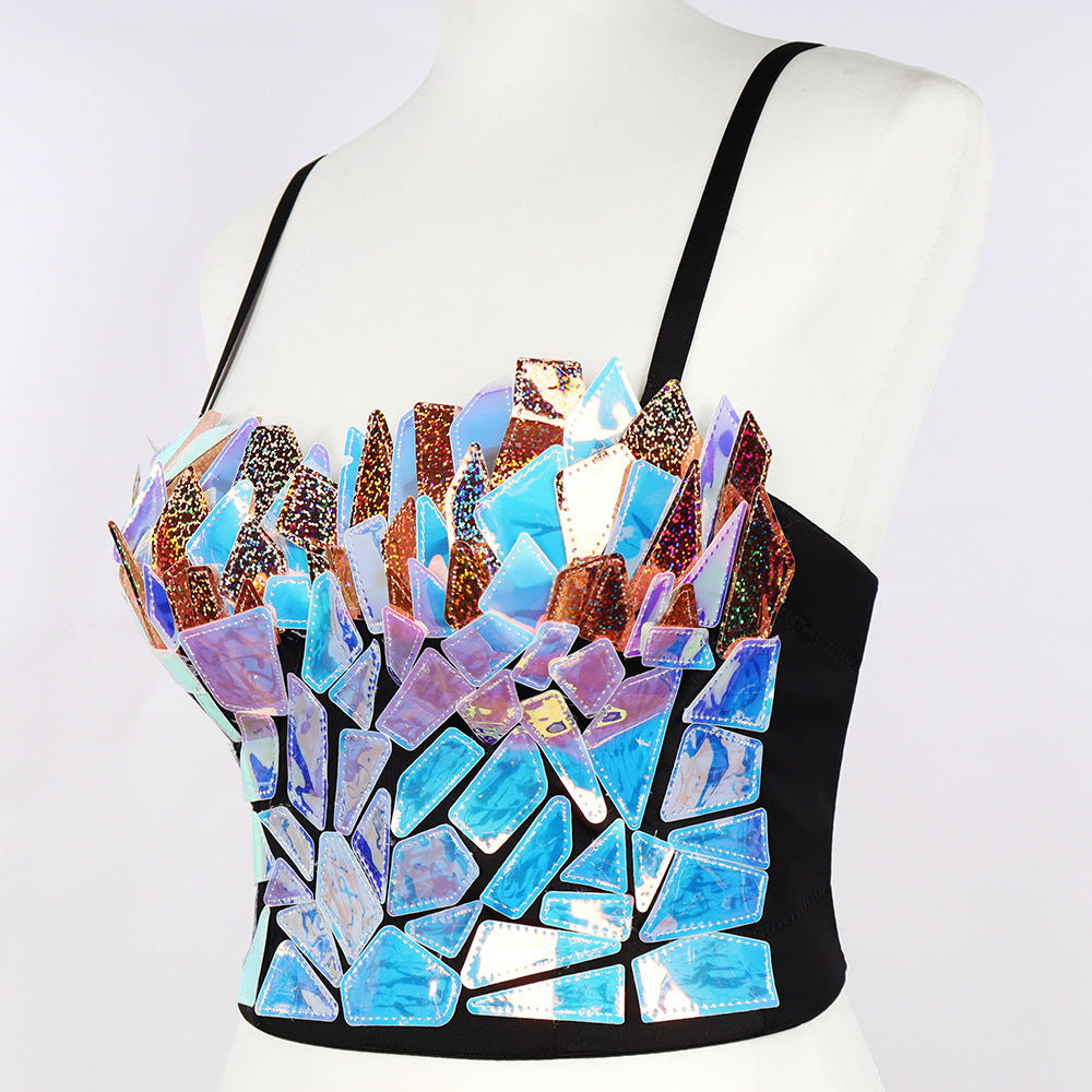 Mannequin wearing a striking iridescent mosaic crop top with shattered mirror fragments in holographic blue, purple, and copper tones on a black base. Features thin black shoulder straps and a bold, reflective fragmented design.