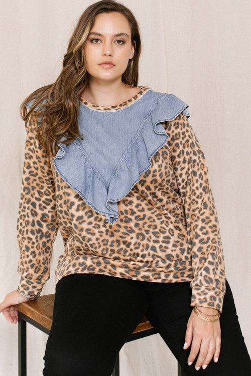 Woman wearing a leopard print top with denim collar against a beige background