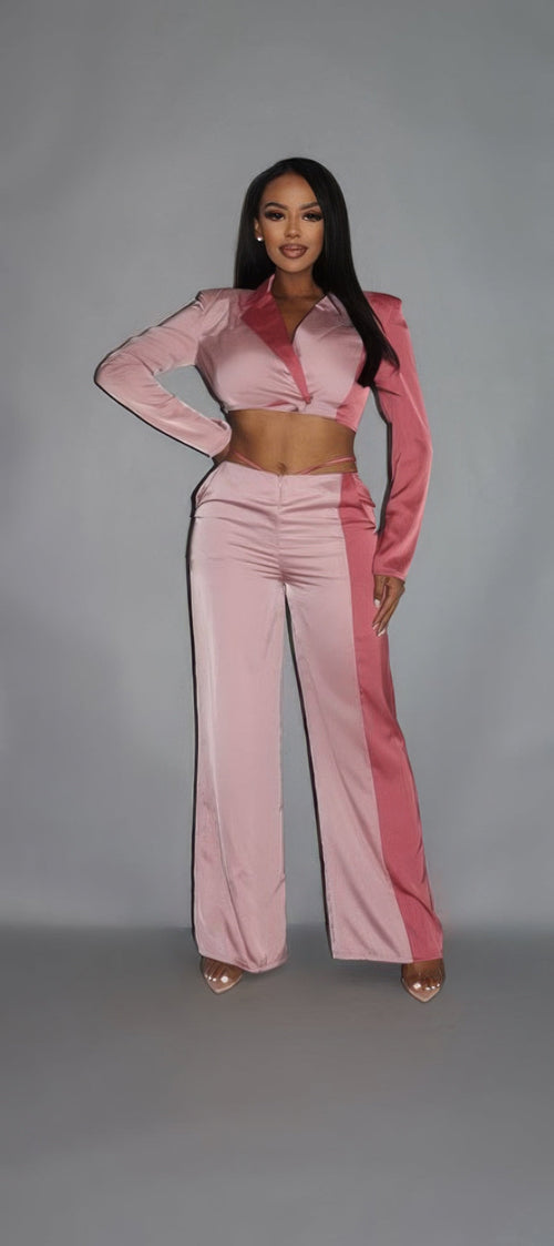 Woman wearing a pink outfit with a high collar against a gray background