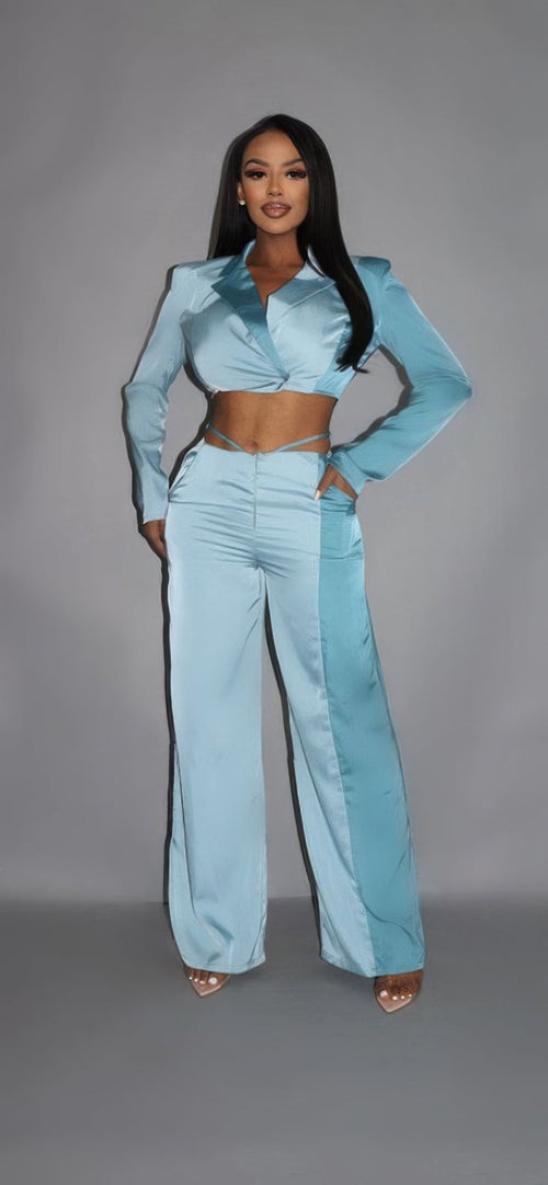 Woman wearing a two-tone blue satin two-piece set with a cropped wrap blazer top, wide-leg pants, and nude heels.