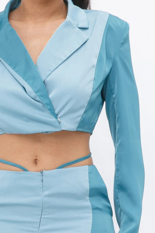 Close-up of a two-tone blue satin two-piece set with a cropped wrap blazer top and matching high-waist skirt.