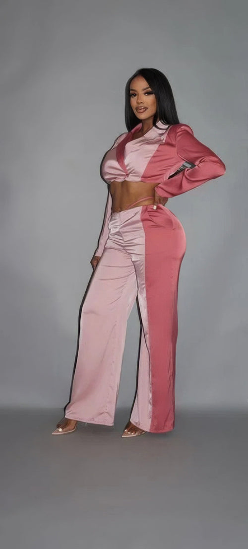 Side view of a woman wearing a two-tone pink satin cropped wrap blazer and matching wide-leg pants with nude heels.
