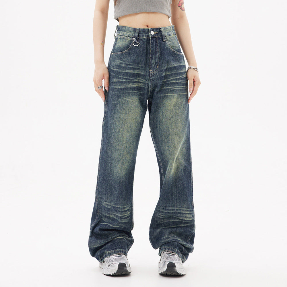 Woman modeling dark blue wide-leg baggy jeans with faded wash and front pockets, paired with a grey crop top and chunky sneakers. Full-body casual street-style fashion shot for Boutique Jolie.